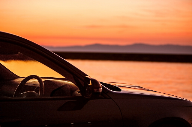 夕焼けに染まる湖畔と車