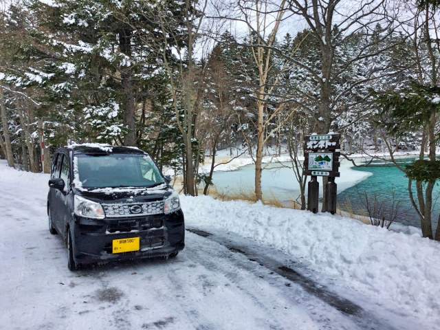 冬の湖畔を走行するレンタカー